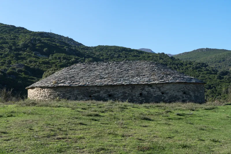 La glacière de Bocca Pruna et son toit de pierre dans une clairière.
