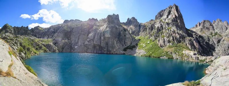 Le lac de Capitello entouré de hautes parois rocheuses en été.